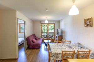 a living room with a table and a red couch at Le Balcon de Barèges - Vue Montagne in Barèges