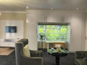 a living room with a table and chairs and a window at Tranquil view lodge in Haenertsburg