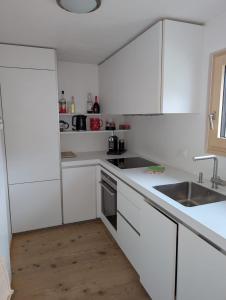 a white kitchen with white cabinets and a sink at Wunderschöne 3 Zimmerwohnung mit Bergblick in Celerina in Celerina