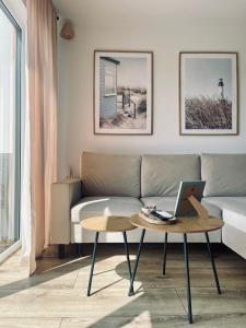 a living room with a couch and a table with a laptop at Morze Na Zawsze in Rewal +59 photos