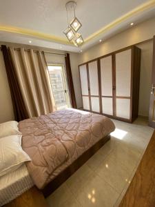 Un dormitorio con una cama grande y una ventana. en Alrehab Cheapest and awesome, en Burg el-Ḥudûd