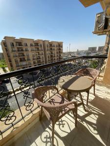 Un balcón con mesas y sillas en un edificio. en Alrehab Cheapest and awesome, en Burg el-Ḥudûd