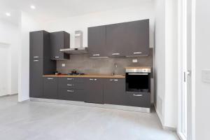 a kitchen with gray cabinets and a sink and a stove at Suite La Fenice - Self Chek-in - WIFI in Novara