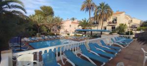 a pool with blue lounge chairs and palm trees at Apartamento Bellaluz 0505 Resort Golf La Manga Club in Cartagena