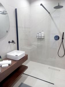 a white bathroom with a shower and a sink at Ianos Living Spaces - 01 in Korinthos +13 photos