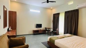 a bedroom with a bed and a chair and a tv at The village vista in Batheri +58 photos
