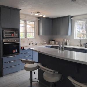 a kitchen with blue cabinets and a counter with stools at Townhouse in Mangrove, St Philip in Saint Philip