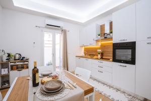 a kitchen with white cabinets and a wooden table at Rena Bianca Apartments in Porto Torres