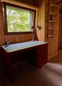 a desk with a lamp in a room with a window at Une jolie Maison en bois au bord de l'Indre in Montbazon