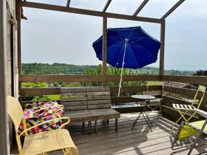 eine Holzbank mit einem blauen Sonnenschirm auf einem Deck in der Unterkunft Les Jardins suspendus in Angoulême