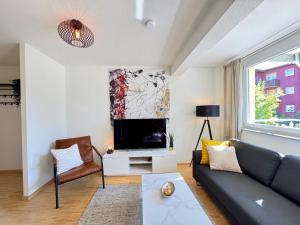 a living room with a couch and a tv at Gartenloft - Design Apartment an der Therme in Bad Krozingen