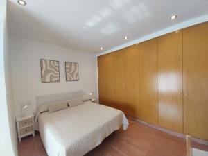 a bedroom with a white bed and wooden cabinets at Casa Santa Úrsula in Casinos