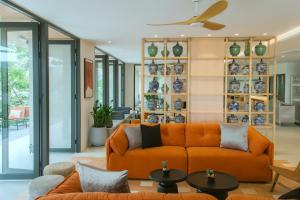 an orange couch in a living room with plates on a wall at PAAK Hotel Suvarnabhumi in Lat Krabang