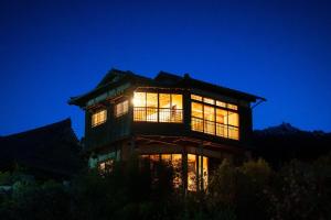 un grand bâtiment avec des fenêtres éclairées la nuit dans l'établissement Beppu Kura, à Beppu