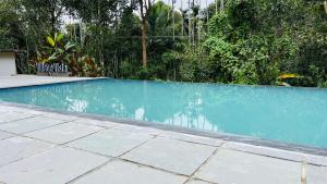 a swimming pool with blue water in a yard at The village vista in Batheri