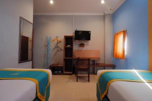 Una habitación con dos camas y un escritorio y un televisor. en Ancora Syariah Hotel Malioboro by Sawiji, en Ngabean