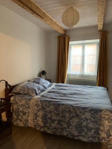 una camera da letto con un letto con una coperta blu e una finestra di Chez Burons&Bouchons, Le Refuge Gourmand et Authentique a Condat