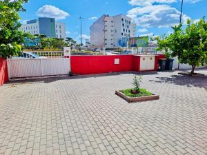 a red wall with a plant in a courtyard at Brincalquimia in Setúbal