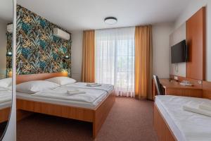 ein Hotelzimmer mit zwei Betten und einem Fernseher in der Unterkunft Wellness Hotel Thermal in Štúrovo