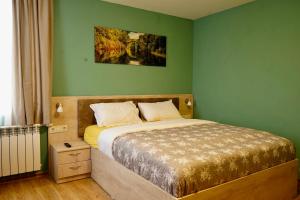 a bedroom with a large bed with green walls at Къща за Гости Тодор in Shiroki Dol