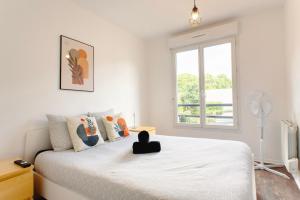 Una habitación blanca con una cama y una ventana en Appartement cosy parking privé, en Saint-Ouen