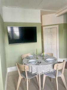 a dining room with a table with chairs and a television at Bridge House in Broadwater