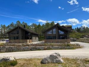 two large wooden homes with a stone wall at New cabin Vrådal - sunny - fantastic hiking areas in Kviteseid