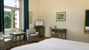 a bedroom with a bed and a chair and a desk at Landhotel Sophienhöhe in Kerpen