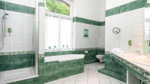 a green and white bathroom with a tub and a sink at Landhotel Sophienhöhe in Kerpen