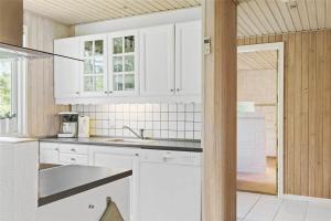 eine Küche mit weißen Schränken und einer Spüle in der Unterkunft 1583 Aakirkeby - Poserekrogen 8 in Vester Sømarken + 14 Fotos