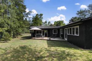 ein schwarzes Haus mit einer Veranda und einer Terrasse in der Unterkunft 1583 Aakirkeby - Poserekrogen 8 in Vester Sømarken