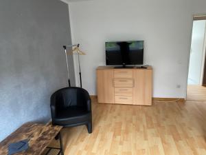 a living room with a tv and a black chair at Alida 2 in Helmstedt