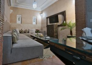 Una sala de estar con un sofá y un televisor en Dar Farah Riad luxe privé, 3ch, piscine chauffée, ptit déj, en Marrakech