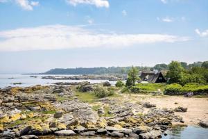 a rocky shore with a house and the water at 5580-Svaneke-Mor-Markers-Gaenge-13 in Svaneke +12 photos