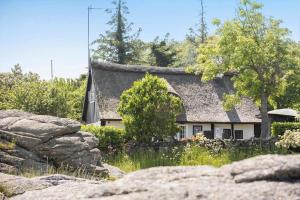 a cottage with a thatched roof with rocks in front at 5580-Svaneke-Mor-Markers-Gaenge-13 in Svaneke
