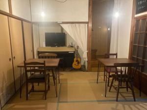 a room with tables and a bedroom with a guitar at お宿とごはん百々 in Tanabe