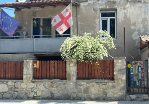 a house with a fence and two flags on a balcony at BMG (Be My Guest) in Mtskheta