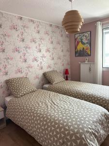 2 camas en un dormitorio con papel pintado con motivos florales en Bel appartement spacieux , lumineux, proche Dijon centre auditorium, en Dijon