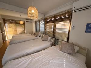 three beds in a room with windows and a chandelier at Yado75 in Nago