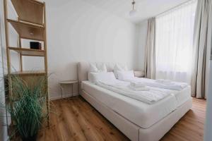 ein großes weißes Bett in einem weißen Zimmer in der Unterkunft Stilvolle Suite in Celle - Frühstück, Kaffee, kostenloser Parkplatz und Wohnküche in Celle