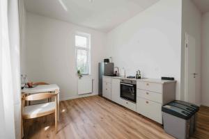 eine weiße Küche mit einem Tisch und einem Kühlschrank in der Unterkunft Stilvolle Suite in Celle - Frühstück, Kaffee, kostenloser Parkplatz und Wohnküche in Celle