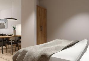 a white bedroom with a bed and a dining room at Galleria Central Apartments & Wellness in Vrchlabí