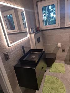 a bathroom with a black sink and a toilet at Appartement Villa du Golf & SPA in Payerne +15 photos