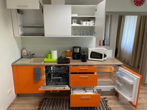a kitchen with orange and white cabinets and a microwave at Family or Group Apartment in Silent Center in Riga