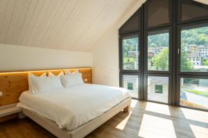 a bedroom with a large white bed and large windows at Chalet con Accesso a SPA Privata in Maso