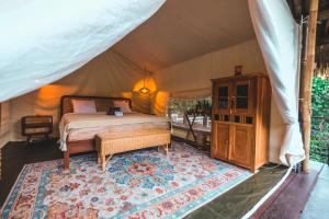 a bedroom in a tent with a bed and a rug at Desa Eko in Munduk