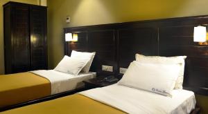 a hotel room with two beds with white and yellow at Ranis Grand in Coimbatore