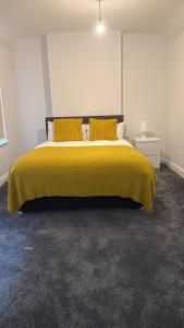 a bedroom with a bed with a yellow blanket at Lovely Room 3 in Avonmouth