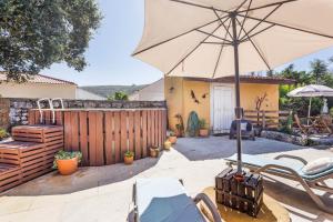 a patio with an umbrella and a table and chairs at Refúgio das Artes Guesthouse in Porto de Mós