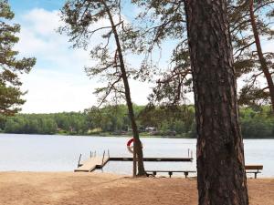a dock on a lake with a bench and trees at 4 person holiday home in Åsljunga in Åsljunga